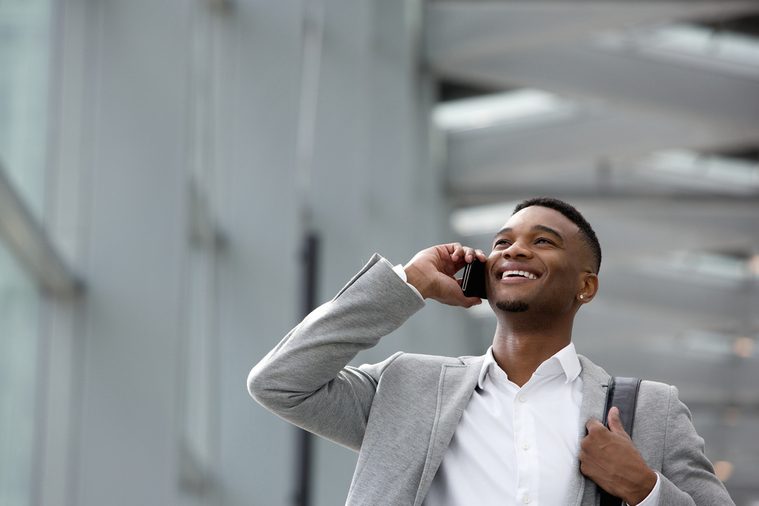 Close up portrait of a happy young man talking on mobile phone inside building