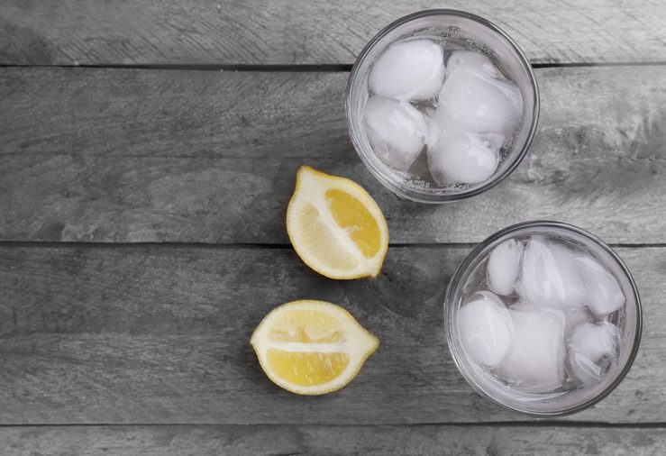 Glasses of water and sliced lemon on wooden table, top view