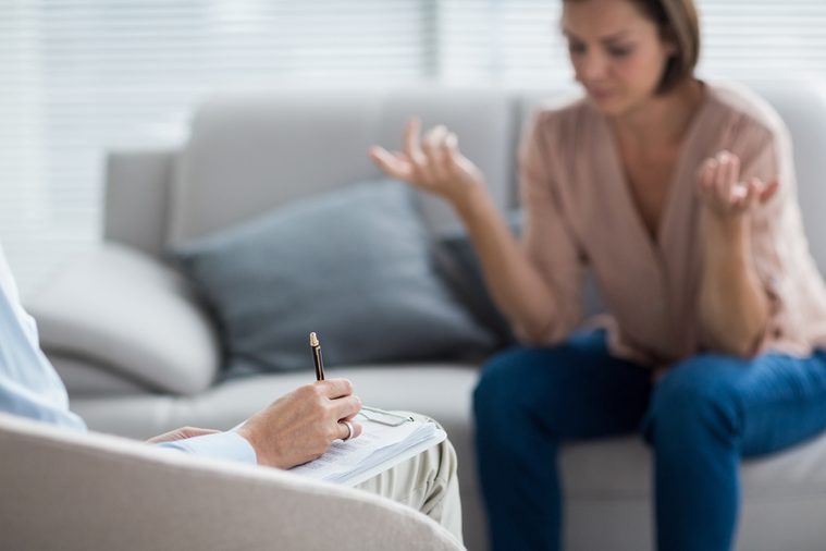 Therapist making notes of patient on sofa at home