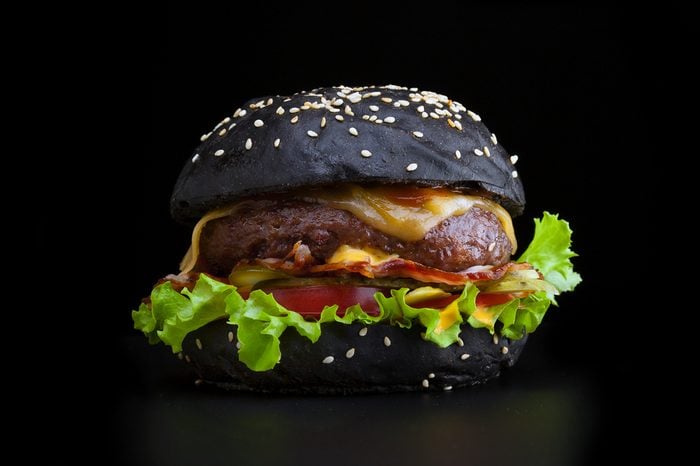 Tasty and appetizing hamburger isolated black with a black bun and bacon.