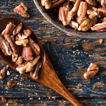 Chopped pecans on a wood spoon