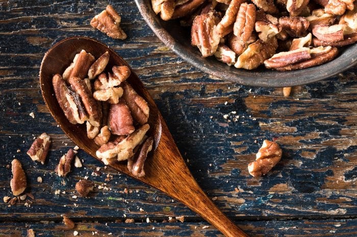 Chopped pecans on a wood spoon