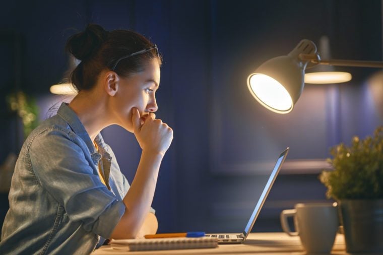 Casual beautiful woman working on a laptop at the night at home.