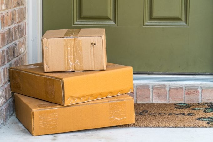 Package delivery on doorstep. Boxes and postal delivery on modern brick home doorstep on front with 3 cardboard boxes