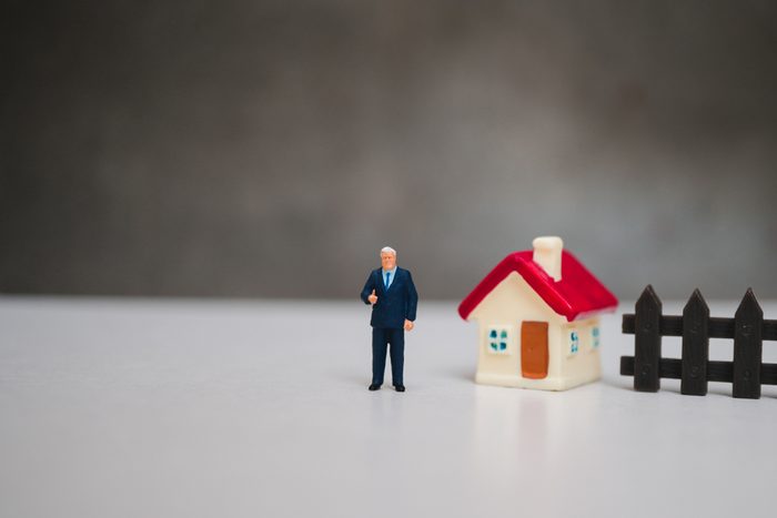 Miniature people, businessman standing with mini house using as business and family concept