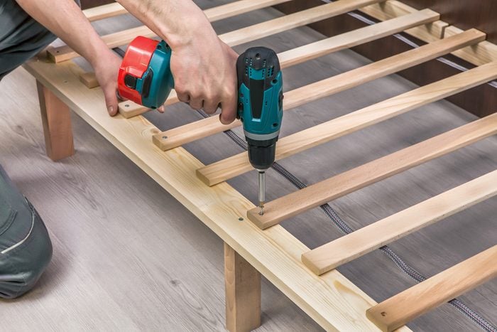 Wooden furniture assembling- woodworker screwing screws using a cordless