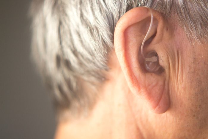 Digital modern hearing aid in the ear of aged old man.