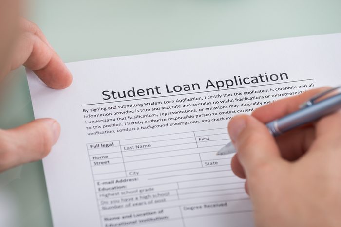 Close-up Of Person Hand Over Student Loan Application Form