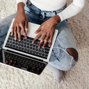 cropped image of african american woman using laptop on floor at home