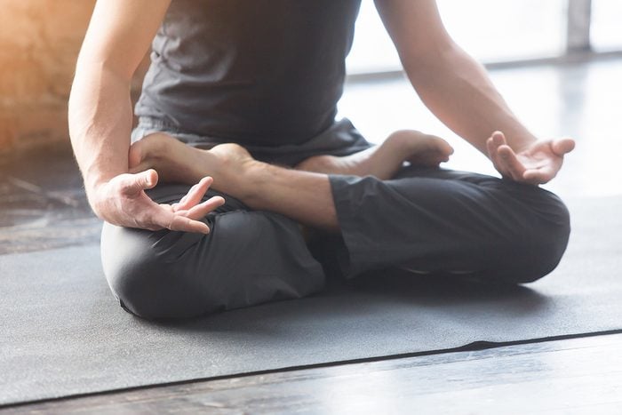 Close up men hands. Young men do yoga indoors on black mat. Guy exercising yoga with a black background in gym. Young men meditating in lotus posture closeup