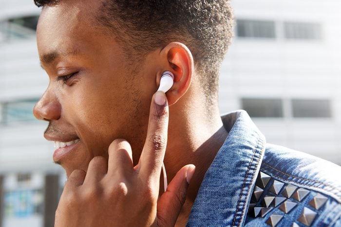 Close up side portrait of attractive man listening to music with finger to ear