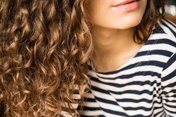 Girl with brown curly hair in a striped T-shirt close-up