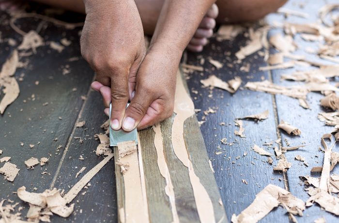 Hands striping glue from parquet wood flooring