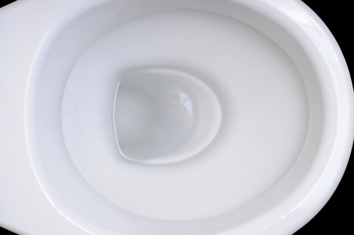 Detail of clean white toilet bowl on black background.