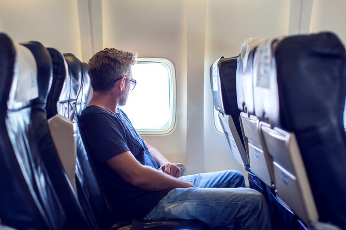 Passenger traveler looking at window in airplane, travel by flight, man tourist sitting in air plane. Travel concept