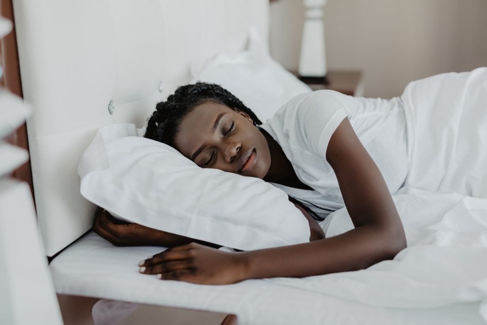 Attraktive junge afroamerikanische Frau wacht in ihrem Schlafzimmer auf