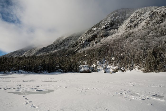 Snow squall over Wildcat Mountain with frozen, snowy pond in foreground, White Mountain National Forest, New Hampshire, USA.