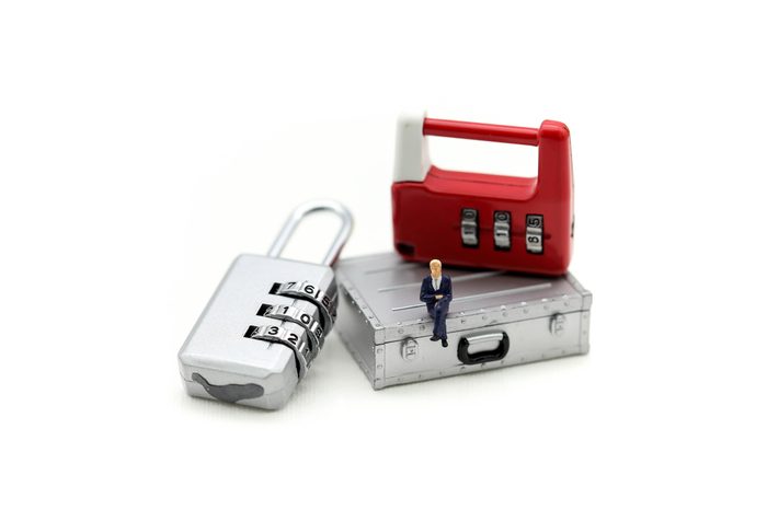 Miniature people : businessman sitting on metal security lock key.