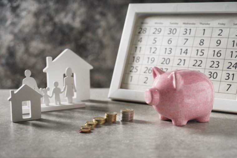 Composition with piggy bank, calendar and model of house and family on grey table. Concept of saving money for buying new house