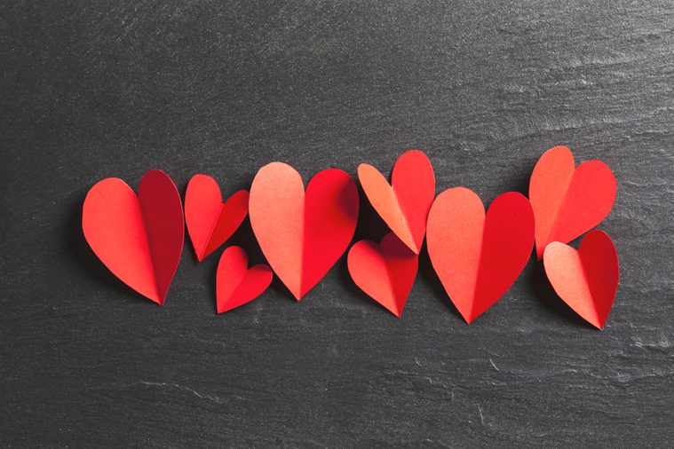 Red handmade paper hearts on a slate background