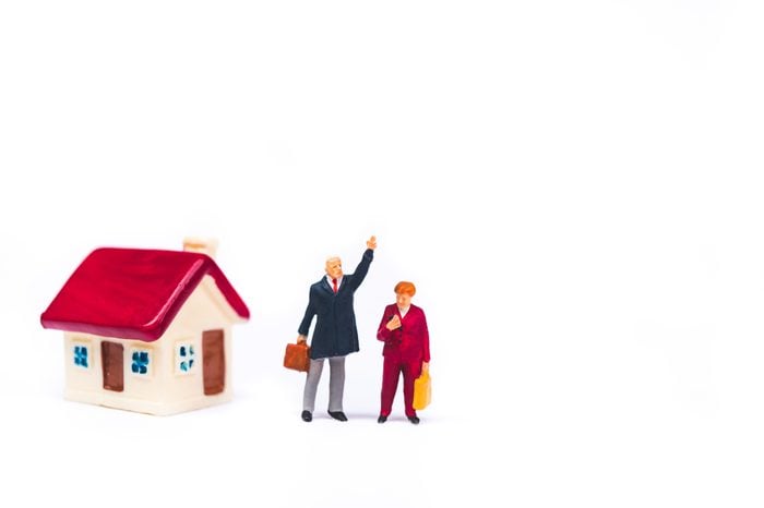 Miniature people, man and woman standing at mini house isolated on white background using as business and family concept