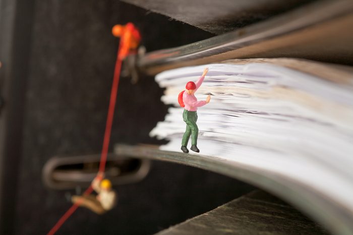 Miniature people group of climbers ascending document binders