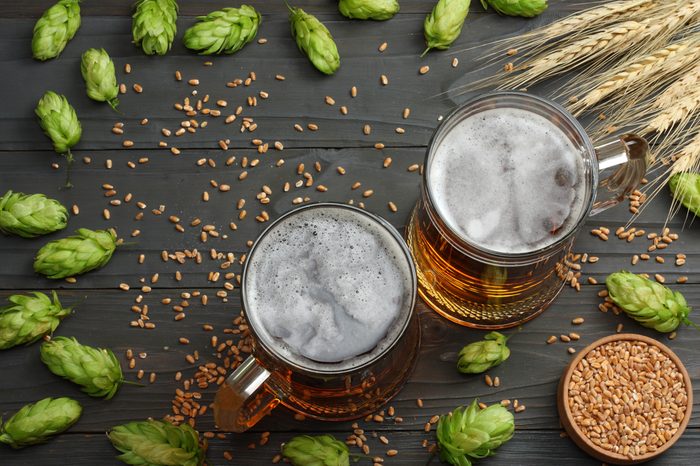Glass beer with hop cones and wheat ears on dark wooden background. Beer brewery concept. Beer background. Top View