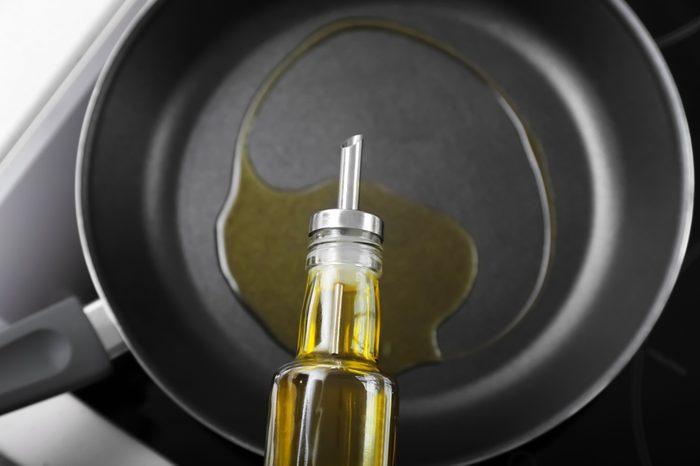 Pouring olive oil onto frying pan on stove