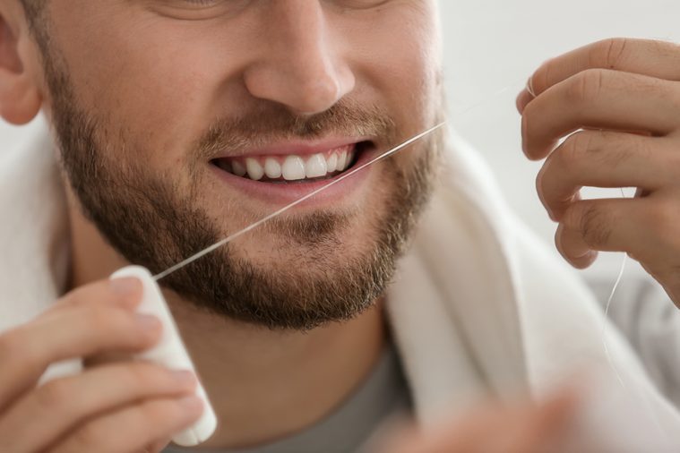 Young man flossing teeth, closeup