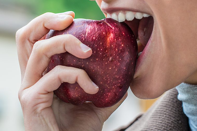 a young attractive girl eats an apple