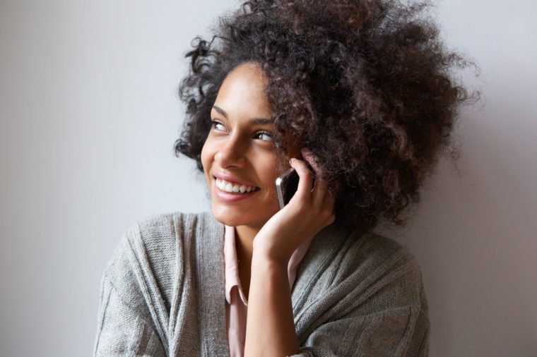 Close up portrait of a cheerful young woman talking on mobile phone