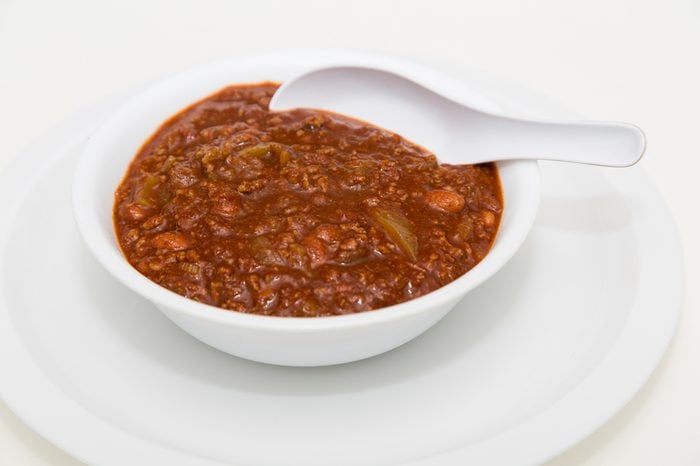 A white bowl of hot, spicy chili with meat and beans