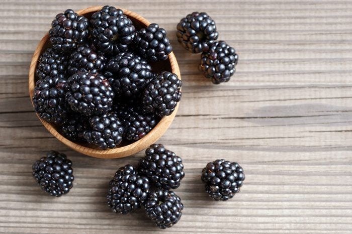Deluxe blackberries in bowl on wooden background. Close up, top view, high resolution product. Harvest Concept