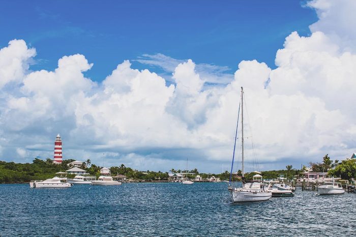 View of Hope Town harbour with lighthouse, sailboat and beautiful sky on a sunny day. Hope Town, Elbow Cay, Abaco, Bahamas