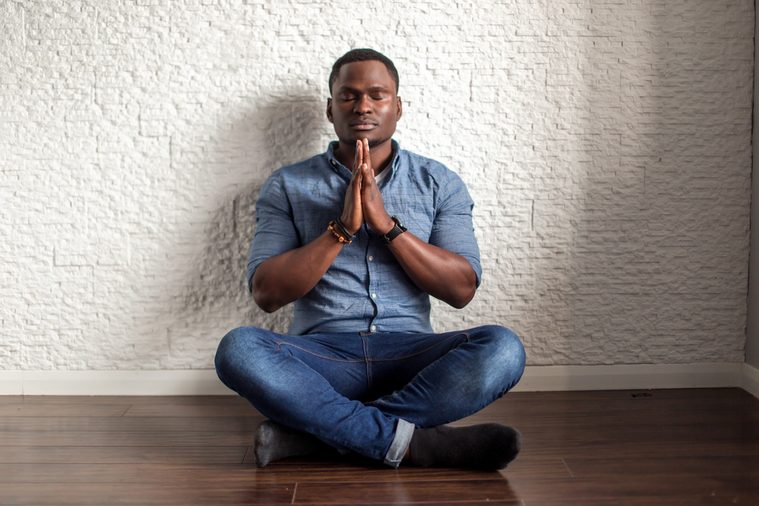Relaxed handsome african young man sitting and meditating on office