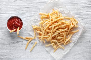 Yummy french fries and sauce in small bowl on wooden background