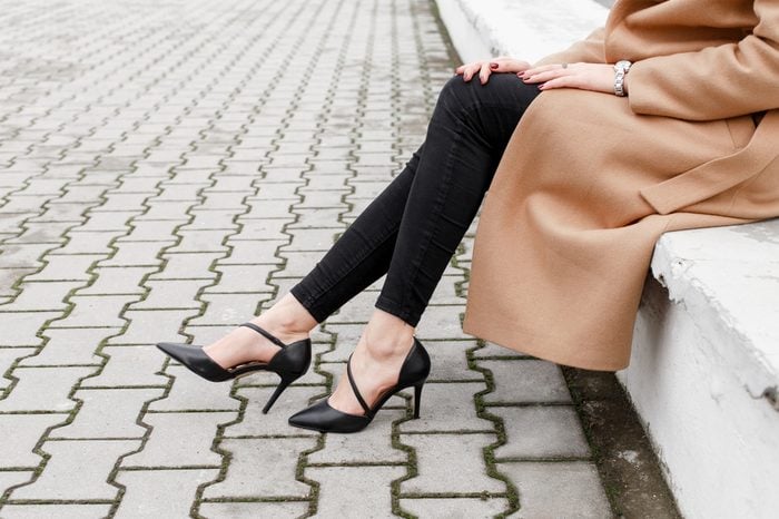 Women's legs in black high heel shoes and black jeans in the city street. Trendy elegant casual outfit. Details of everyday look. Street fashion.