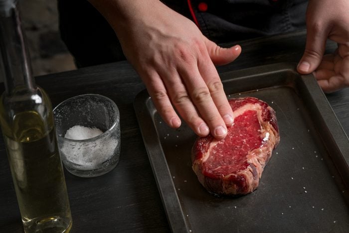 Chef hands cooking steak in the kitchen on the classic recipe on the grill pan. Cook on a dark background for text or design, horizontal photo.