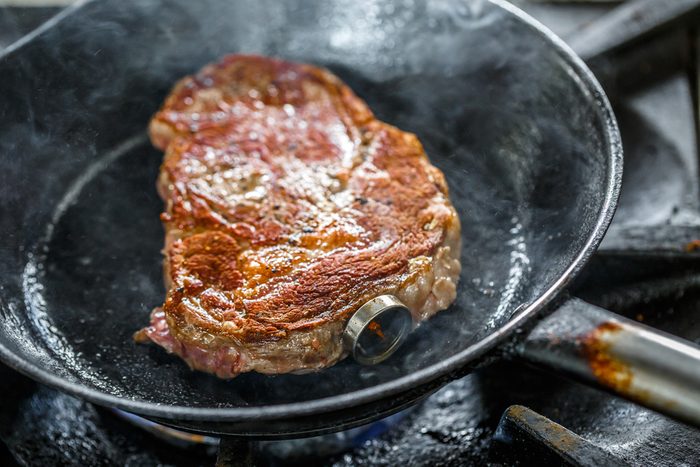 Grilled pork steak with meat thermometer in a frying pan
