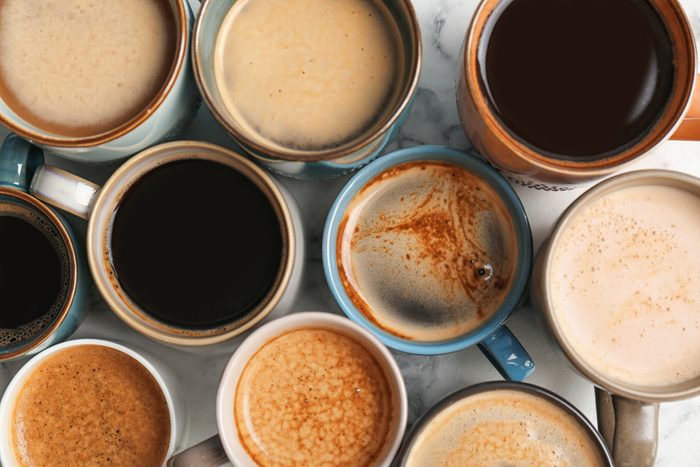Many cups of different aromatic hot coffee on table, top view