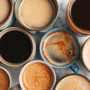 Many cups of different aromatic hot coffee on table, top view