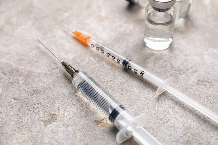 Syringes with ampule on grey background