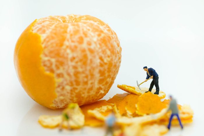 Miniature people: Worker working on the orange peel to clean it using for creativity , artwork business concept.
