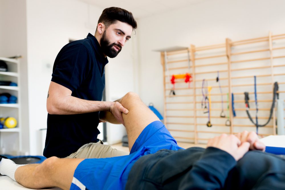 Male therapist treating knee of sporty patient