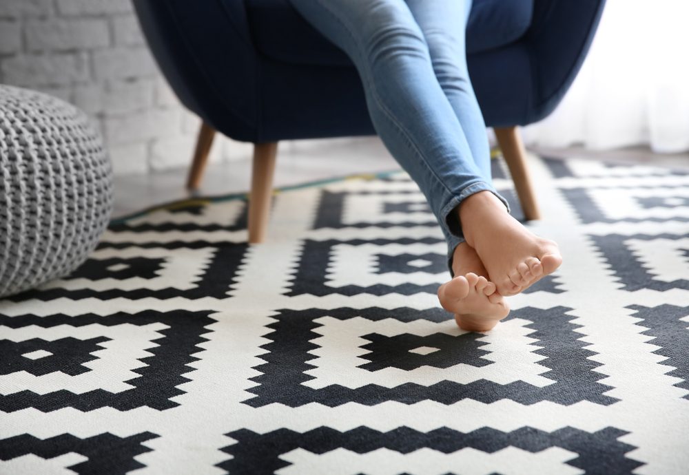 Woman sitting in armchair with feet on carpet at home