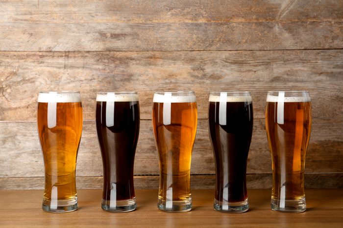 Glasses with beer on table against wooden background