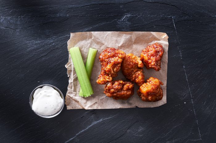 bbq chicken hot wings on parchment paper with ranch and celery