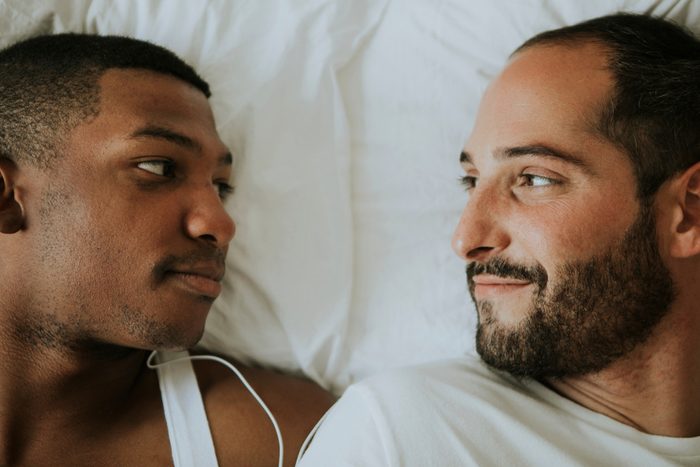 Gay couple cuddling in bed