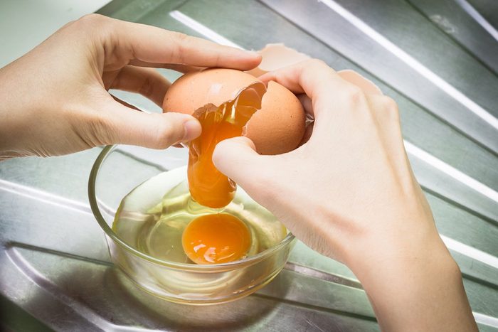 Closeup of a pair of hands cracking an egg into a glass bowl