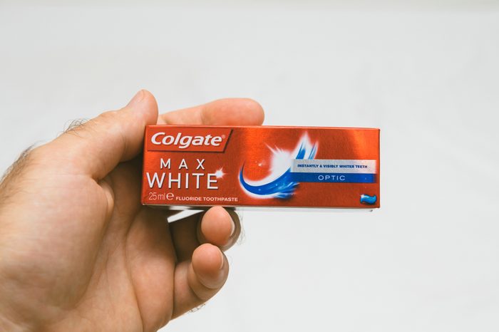 PARIS, FRANCE - JUL 27, 2018: Man holding Colgate small air security rules conformed travel toothpaste against white background